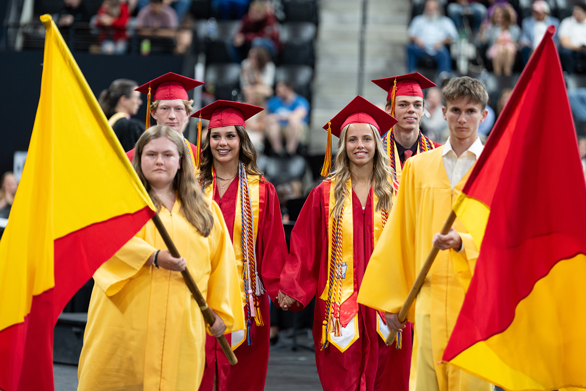 Row of students, some holding flags, at the Coronado High School graduation ceremony.