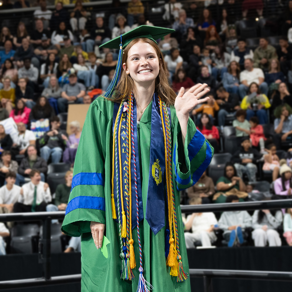 Graduate Evelyn Ecks smiling and waving as she walks across the stage.