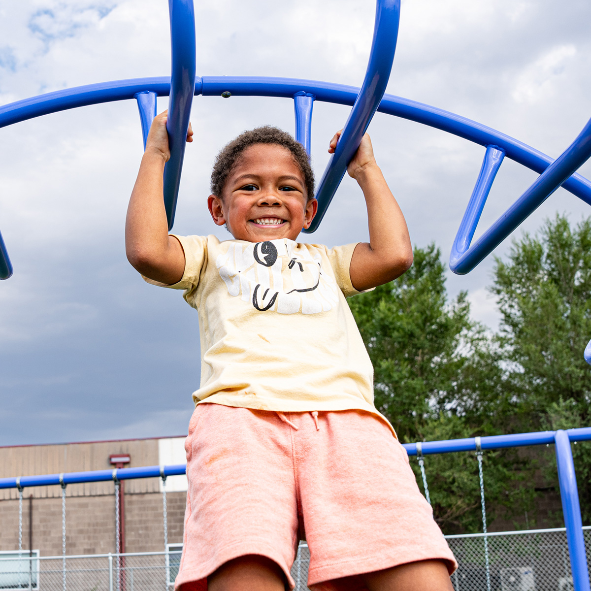 Child laughing while playing on a new playground structure.